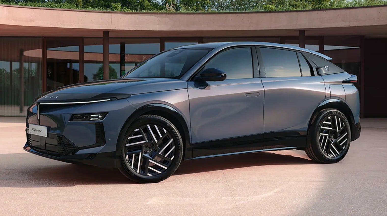 Blue-gray crossover SUV with large alloy wheels parked in front of a modern building, sunlight reflecting off the sleek body.