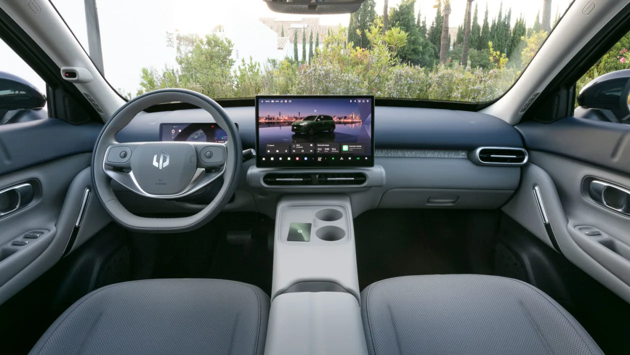 Modern car interior featuring a large tablet-style center touchscreen and digital instrument cluster behind the steering wheel.