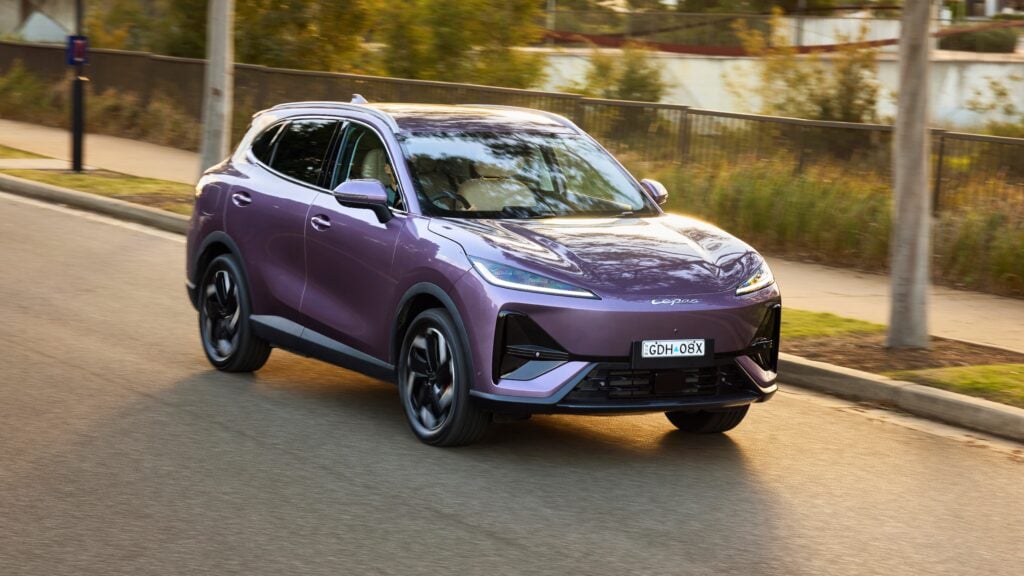 Purple SUV in motion along a suburban street with blurred background and trees.