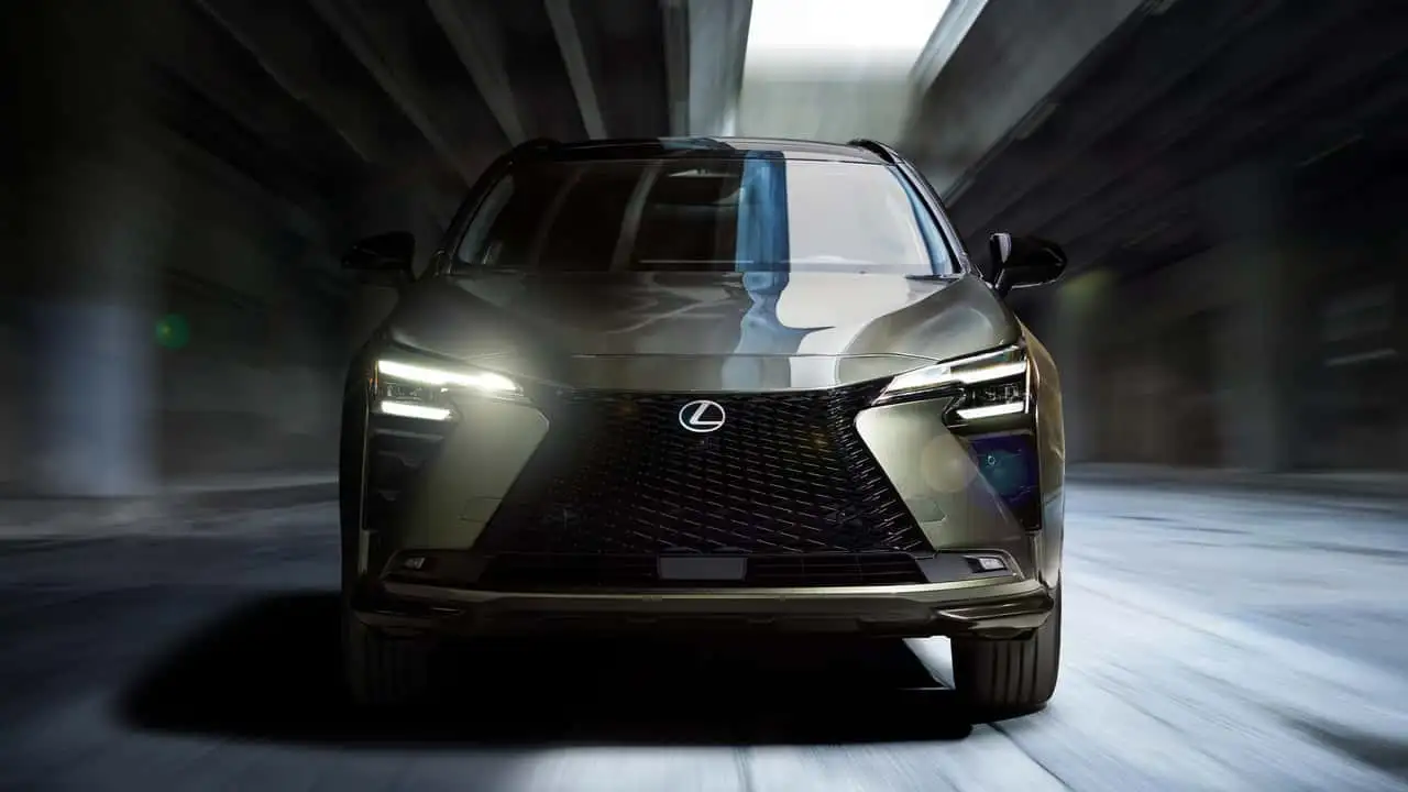 Front view of a silver Lexus SUV with illuminated headlights driving through a tunnel.