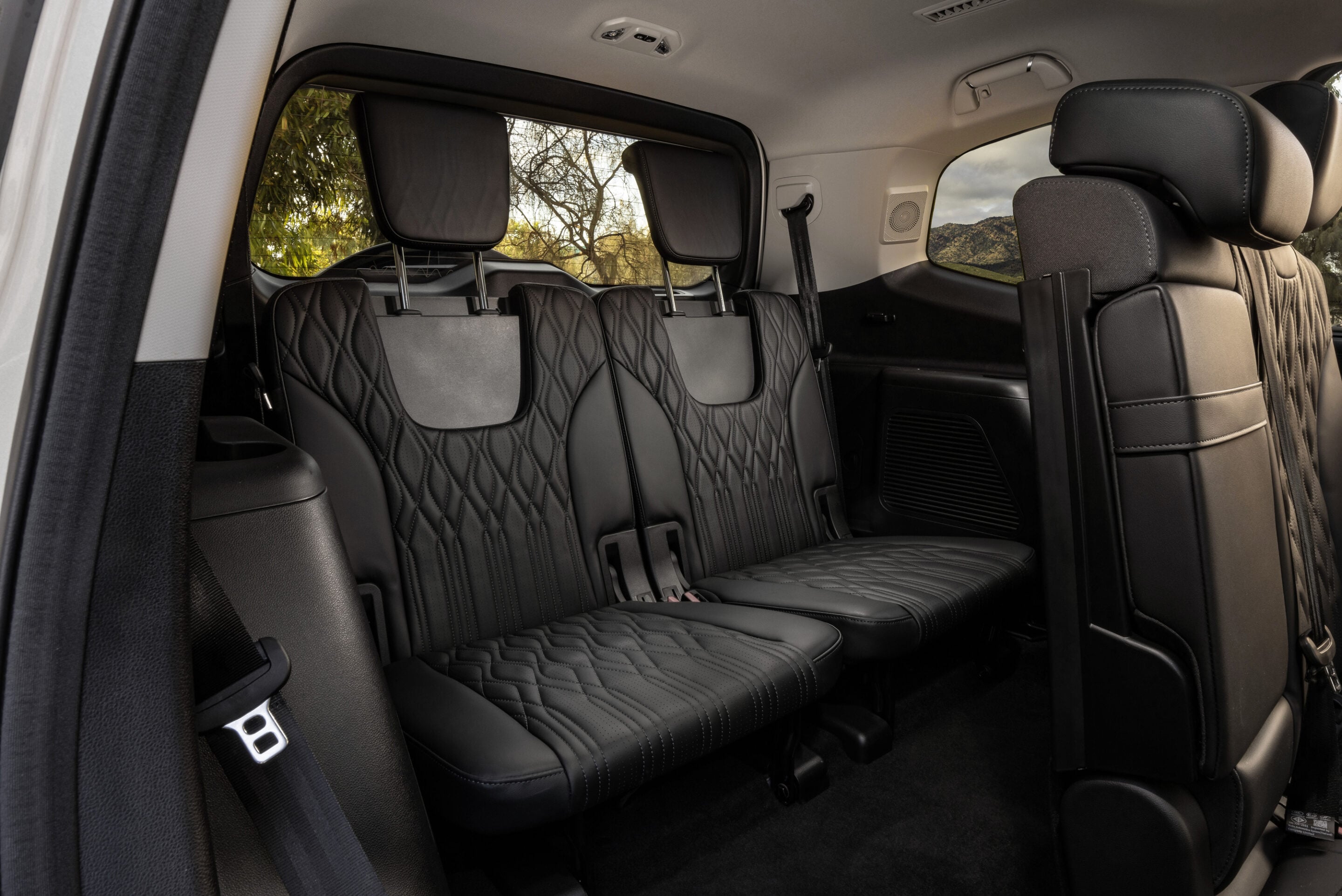 Rear row of black quilted leather seats with matching headrests and visible seat belts in a car interior.