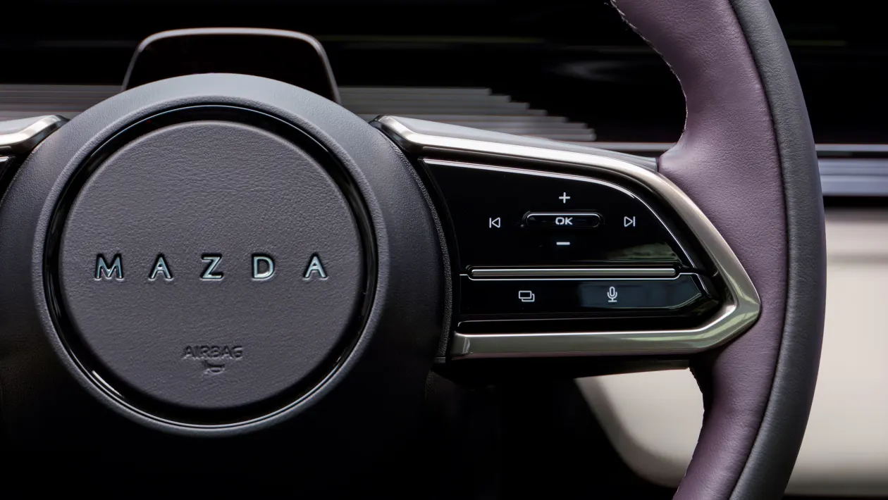 Mazda steering wheel close-up with a right-side control panel of multimedia buttons