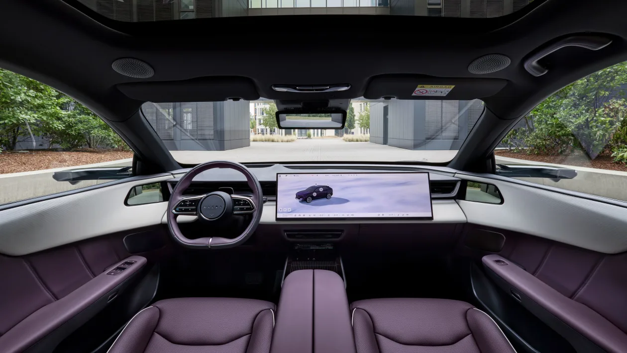 Interior view of a modern car with a long horizontal touchscreen dashboard and purple leather seats, seen from the back seat toward the windshield.