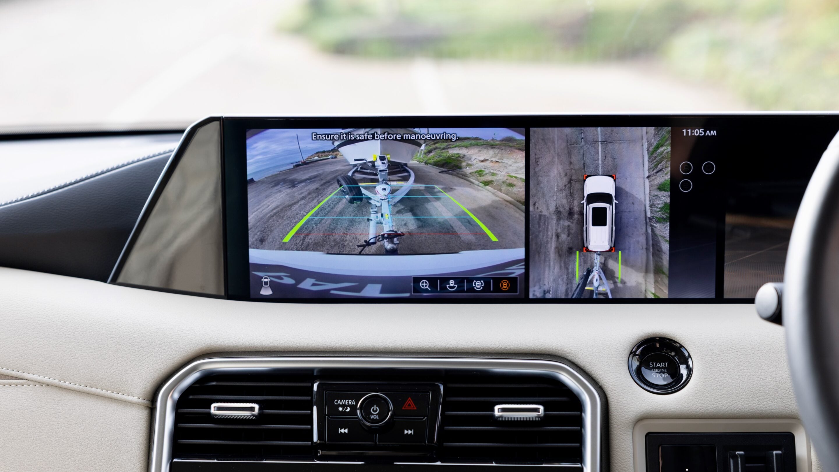 In-car display showing rear-view and top-down parking camera guides for backing up a trailer.