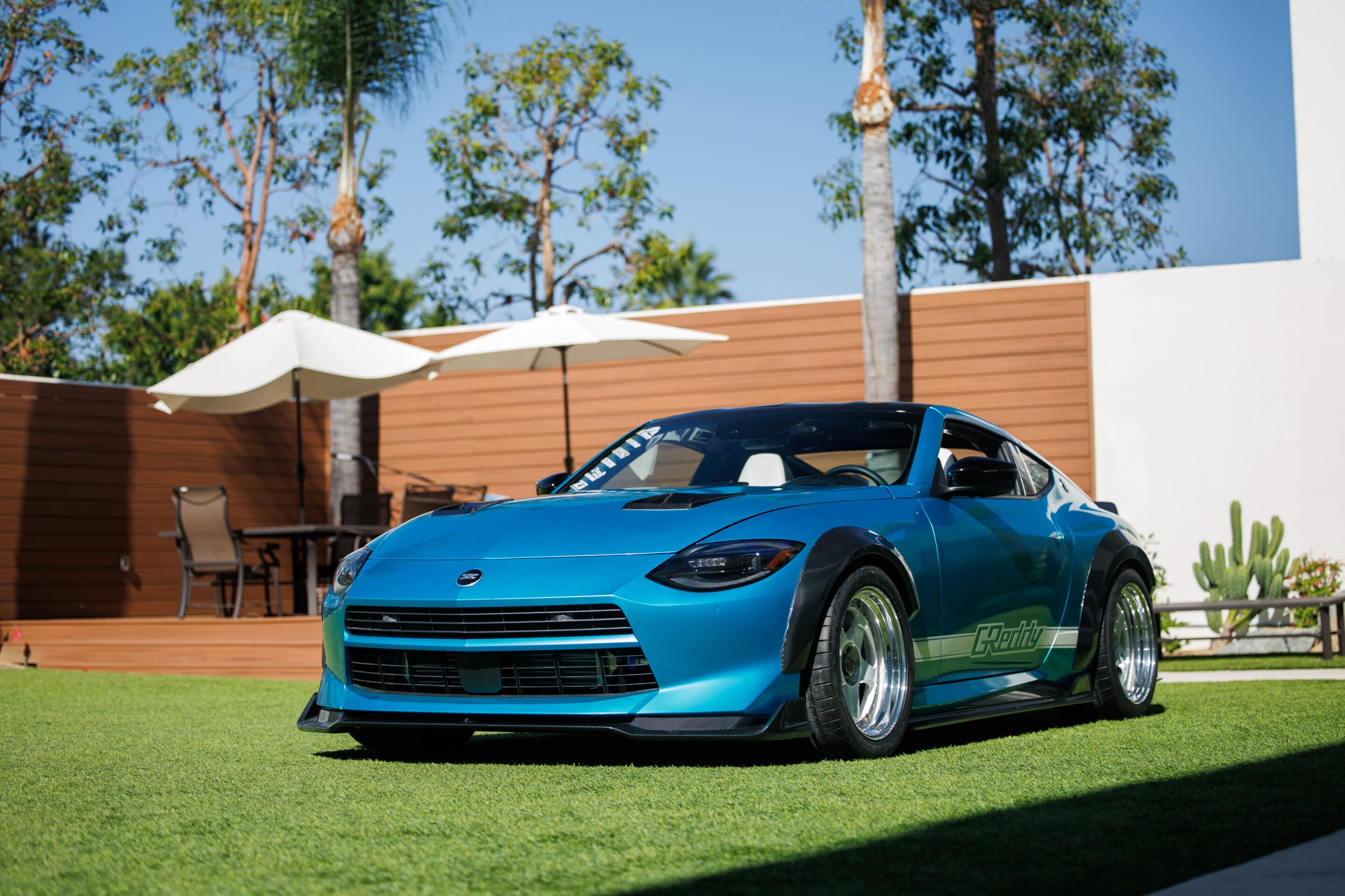 Front left 3/4 view of the Nissan Z Kaze Concept parked in front of a fence with trees in the background