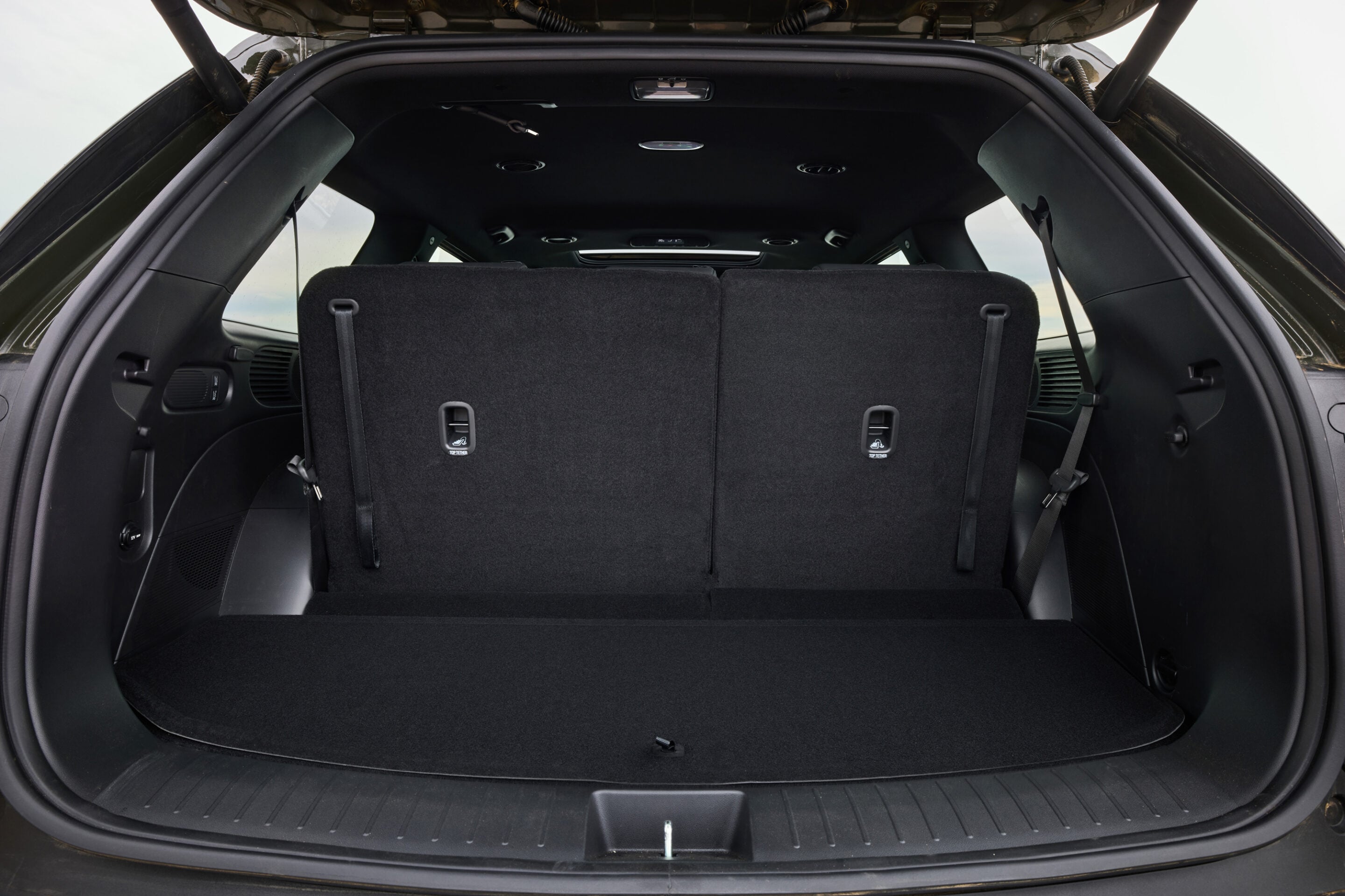 Cargo area of a black SUV with rear seats folded upright, creating a large storage space.