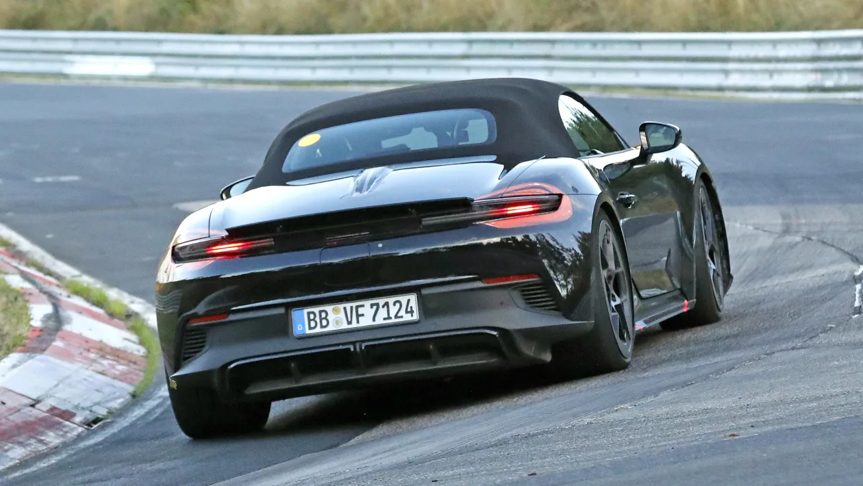 Rear view of a black convertible sports car taking a corner on a race track, red taillights illuminated, German license plate visible (BB VF7124).