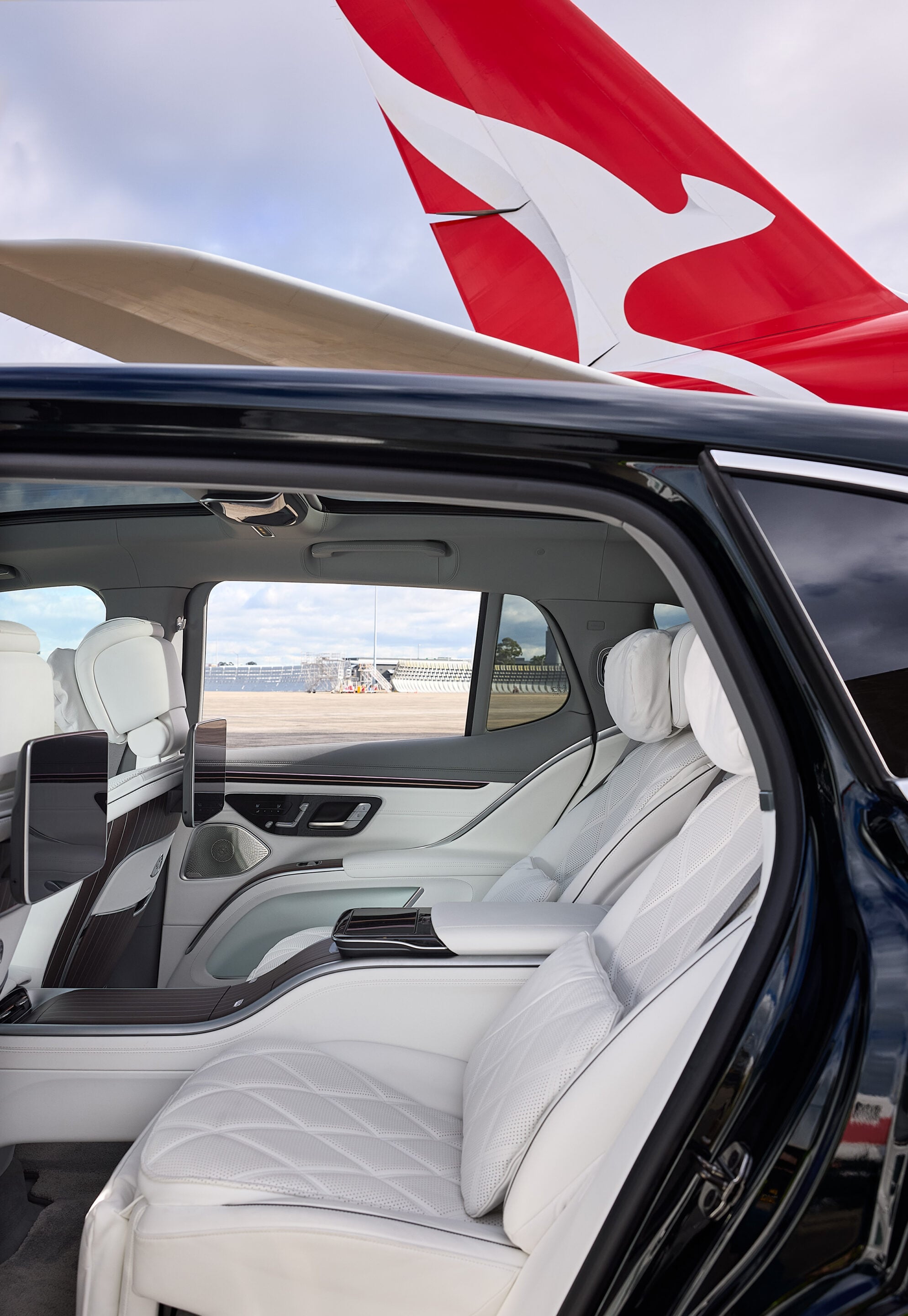 Open SUV door showing white leather interior with quilted seats and a view of the airport tarmac and a red airplane tail outside the window16:9 orientation (informative)