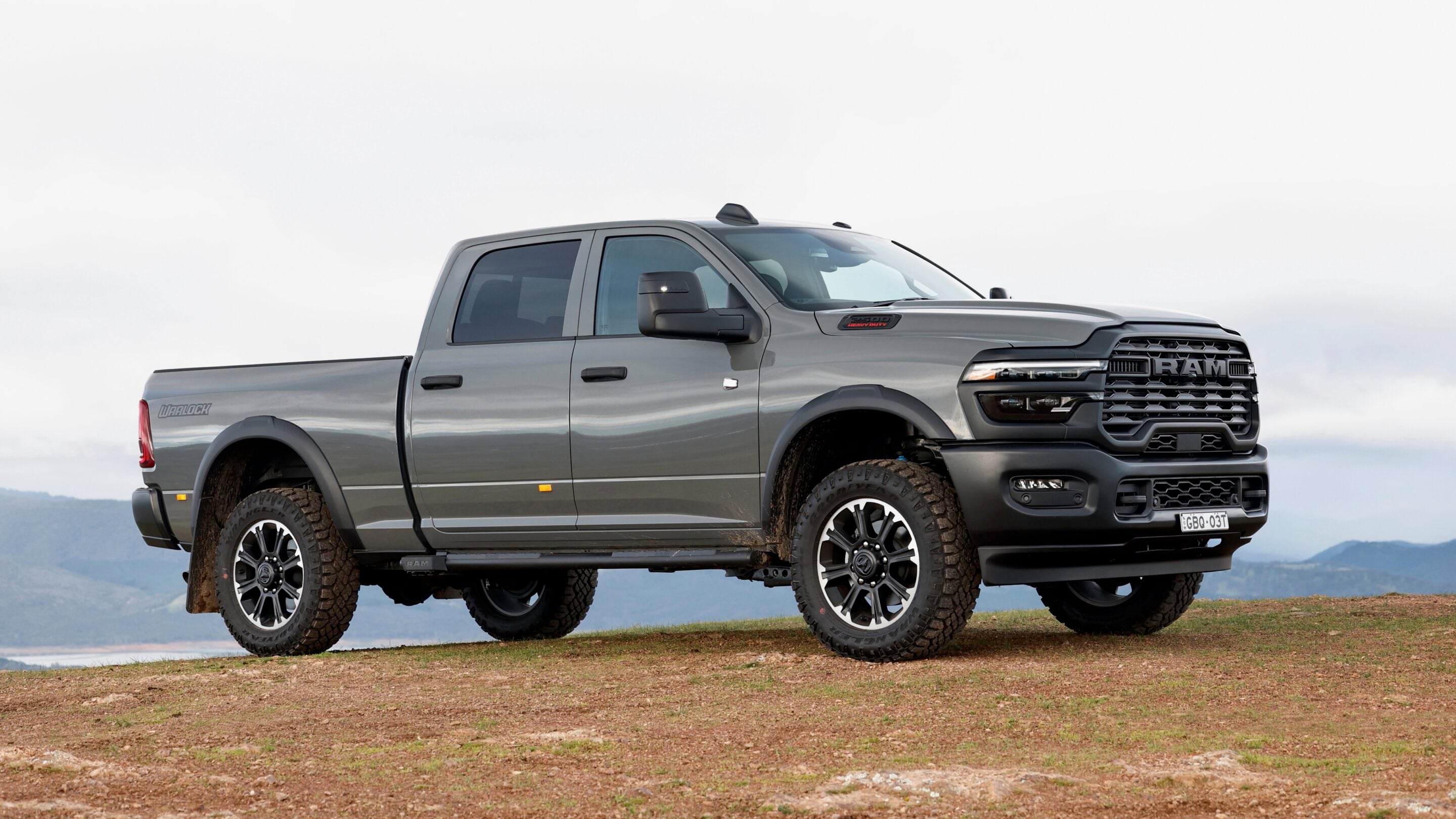 Gray Ram heavy-duty pickup on a dirt hill with distant mountains in the background.