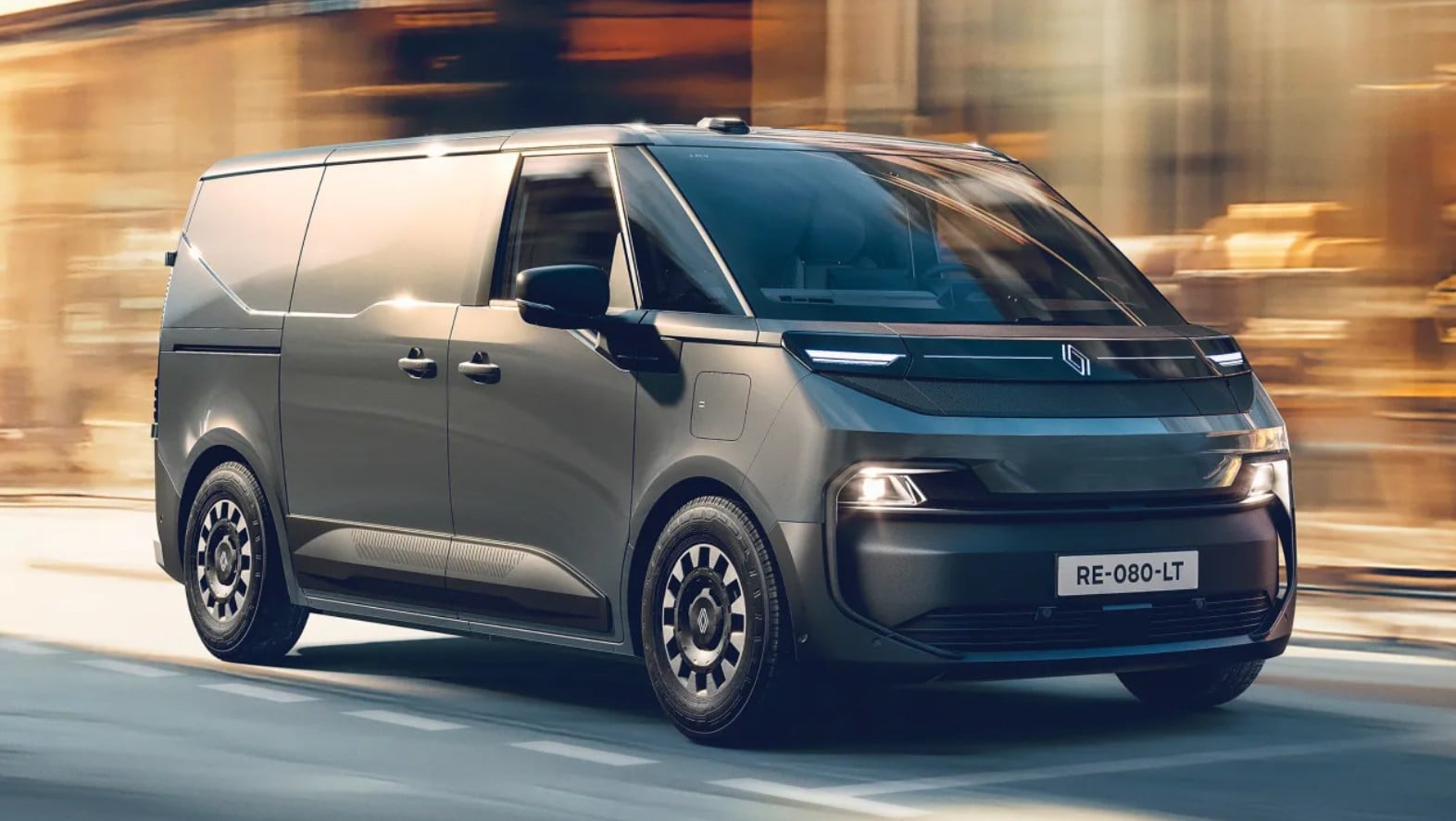 Front three-quarter view of a sleek gray delivery van driving quickly through a city street with blurred background the headlights on and modern design visible.