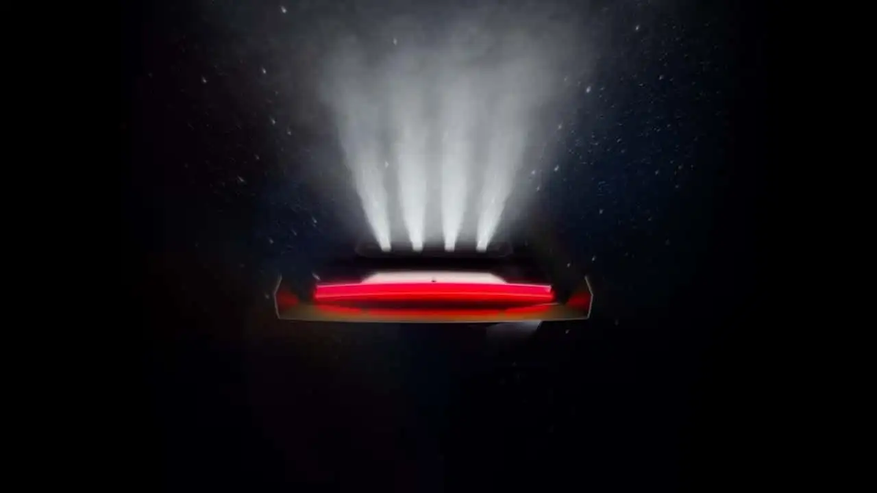 Rectangular electronic device emitting a vertical plume of white vapor with a red glow along its base in a dark setting