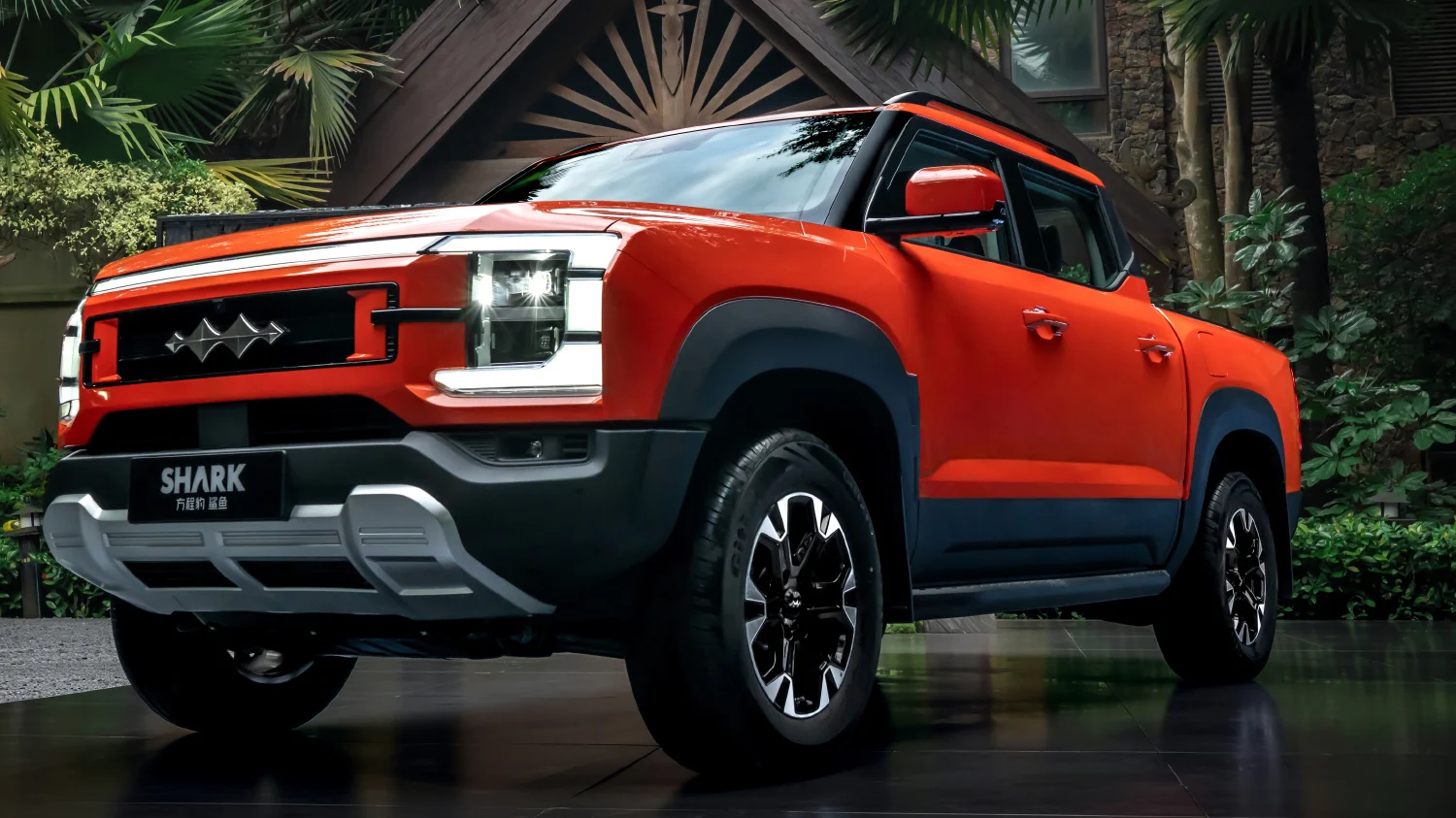 Bright orange pickup truck parked outdoors in a driveway, front view showing bold grille and prominent headlamps.