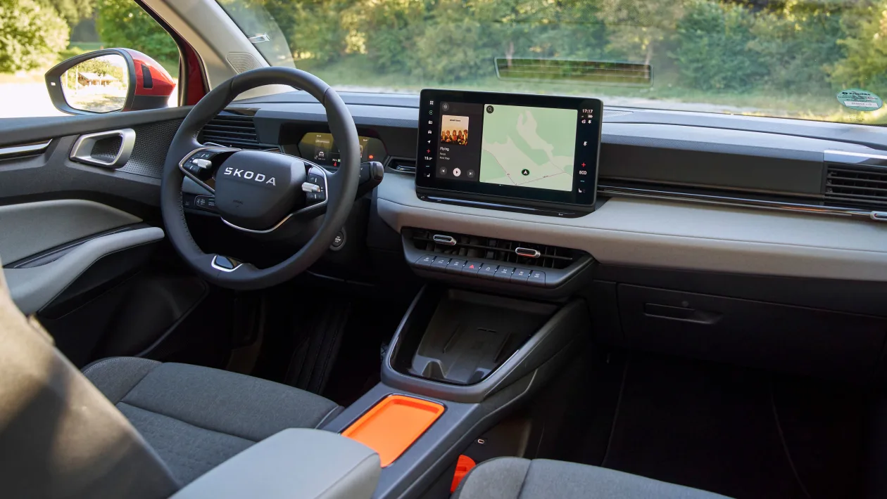 Interior of a modern Skoda car with a large touchscreen navigation on the dashboard and a steering wheel in view.