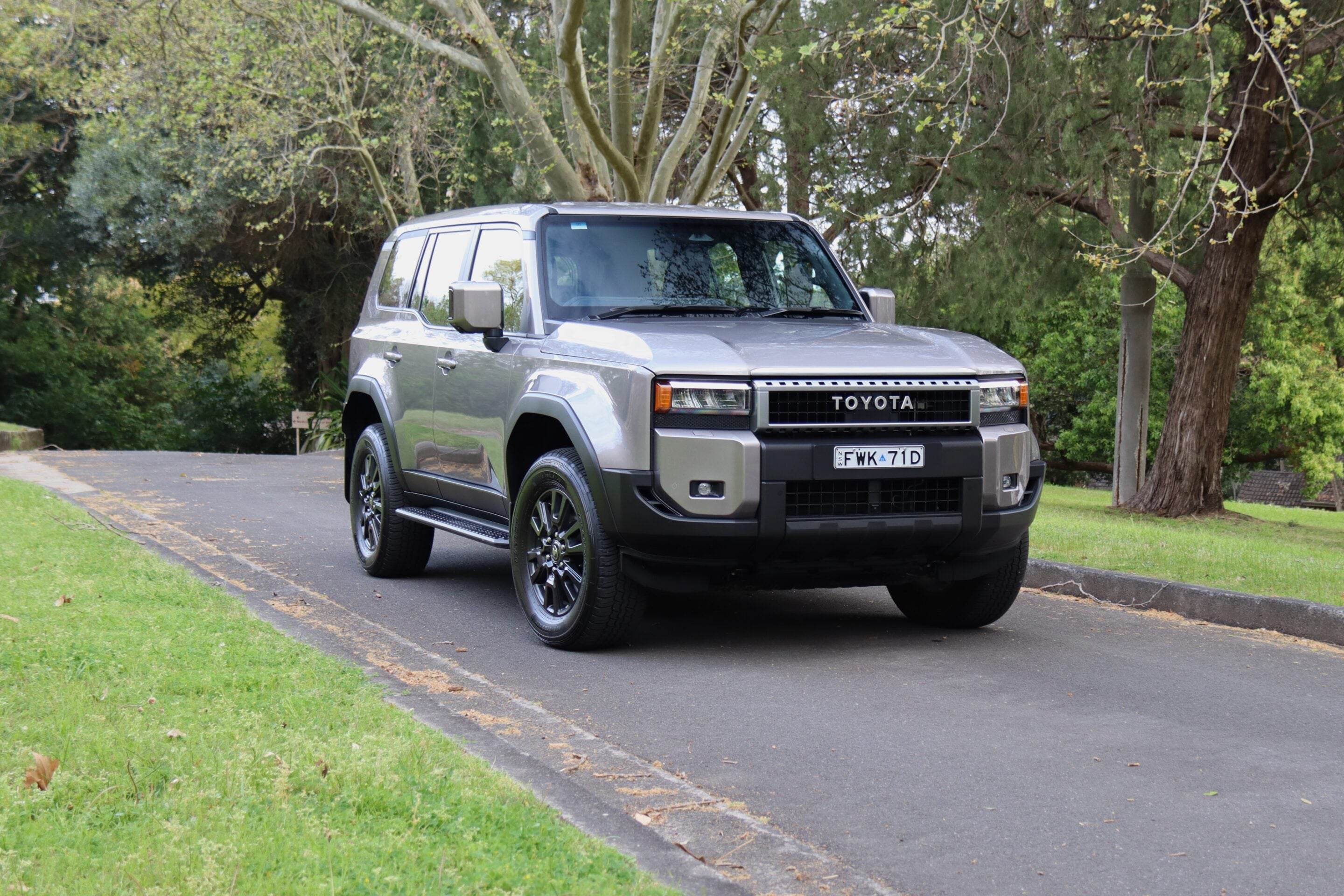 Silver Toyota SUV parked on a residential driveway with trees in the background.