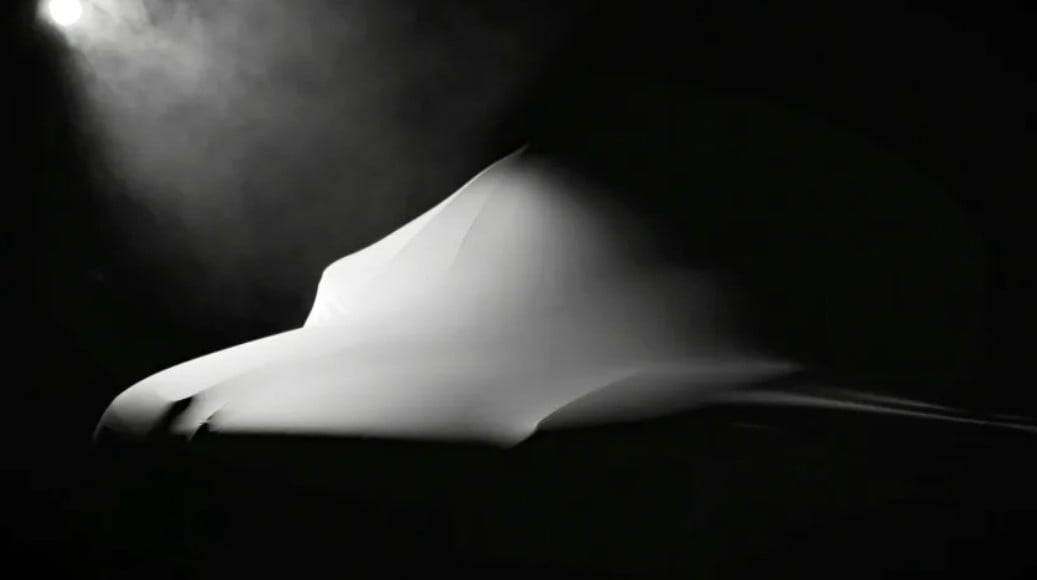 White fabric draped over a form, lit from the left against a dark background, creating smooth curves and shadows.