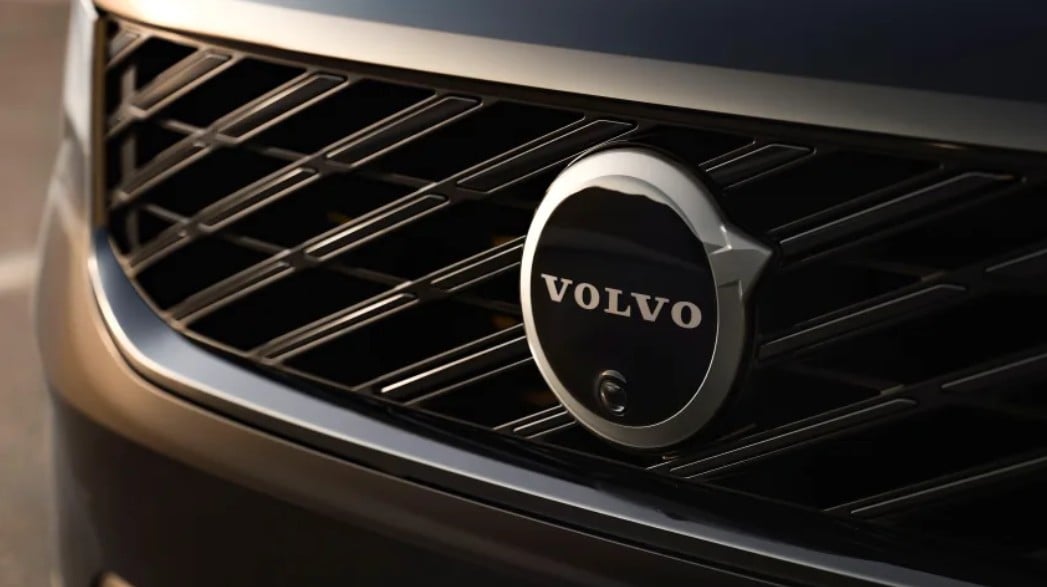 Close-up of a chrome Volvo emblem on the car's front grille, centered.