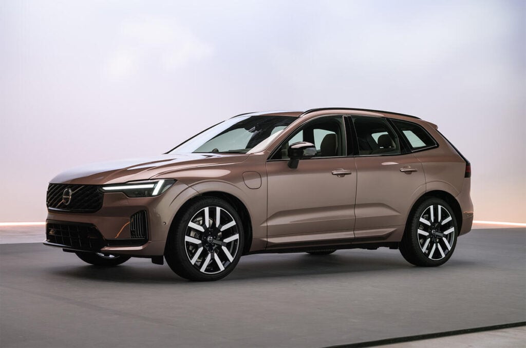 Brown Volvo SUV in a studio, front three-quarter view showing grille, LED headlights, and large multi-spoke wheels.