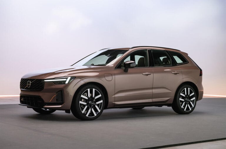 Brown Volvo SUV in a studio, front three-quarter view showing grille, LED headlights, and large multi-spoke wheels.
