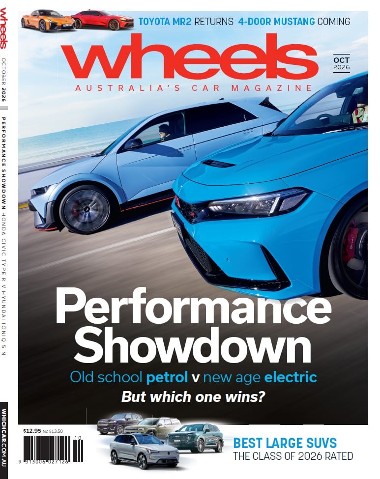 Wheels magazine cover October 2026 showing a blue sports car and a silver car racing along a coast, with the headline 'Performance Showdown' and the subhead 'Old school petrol vs new age electric'