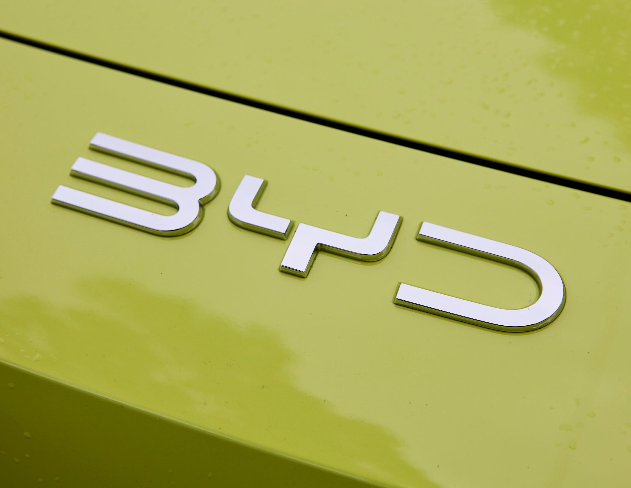 Close-up of white 3D letters on a bright yellow sign, with a black diagonal line across the top-left to bottom-right area.
