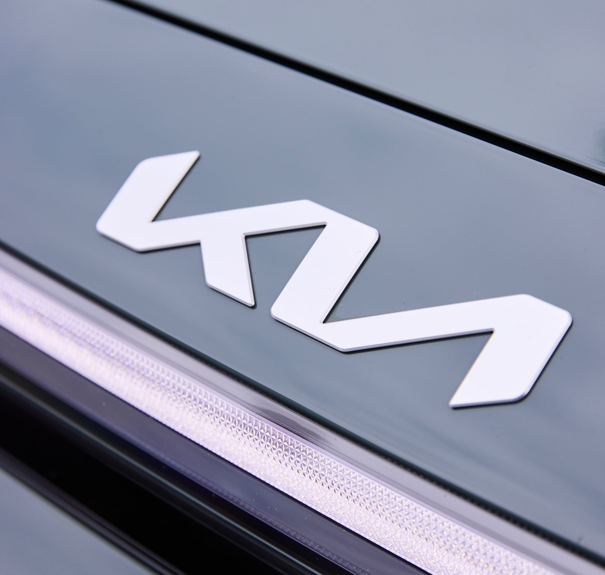 Close-up of a white diamond-shaped car emblem on a metallic blue surface.