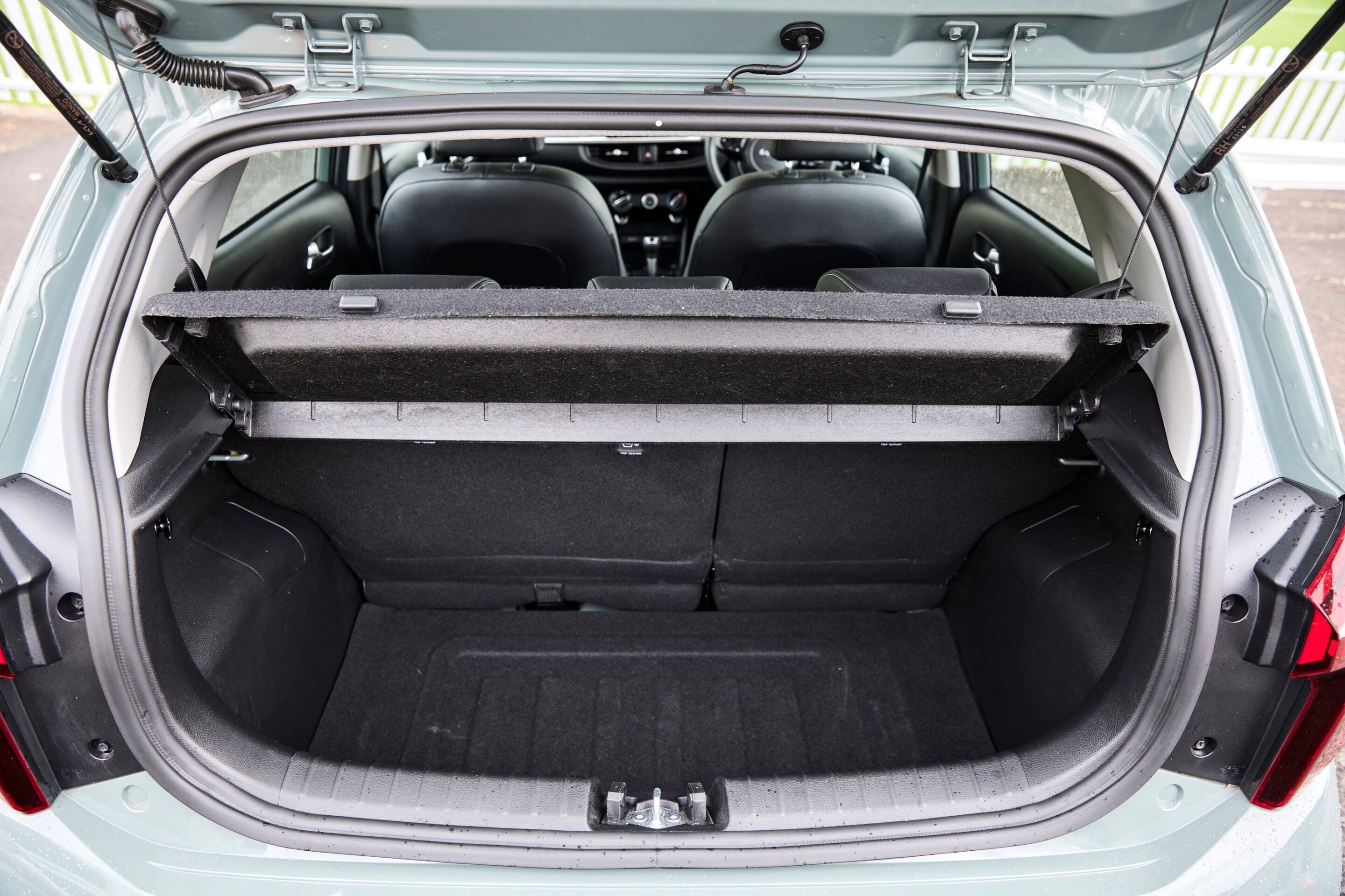 Open hatchback view of car showing empty cargo area with a retractable cover and back seats visible through the rear opening