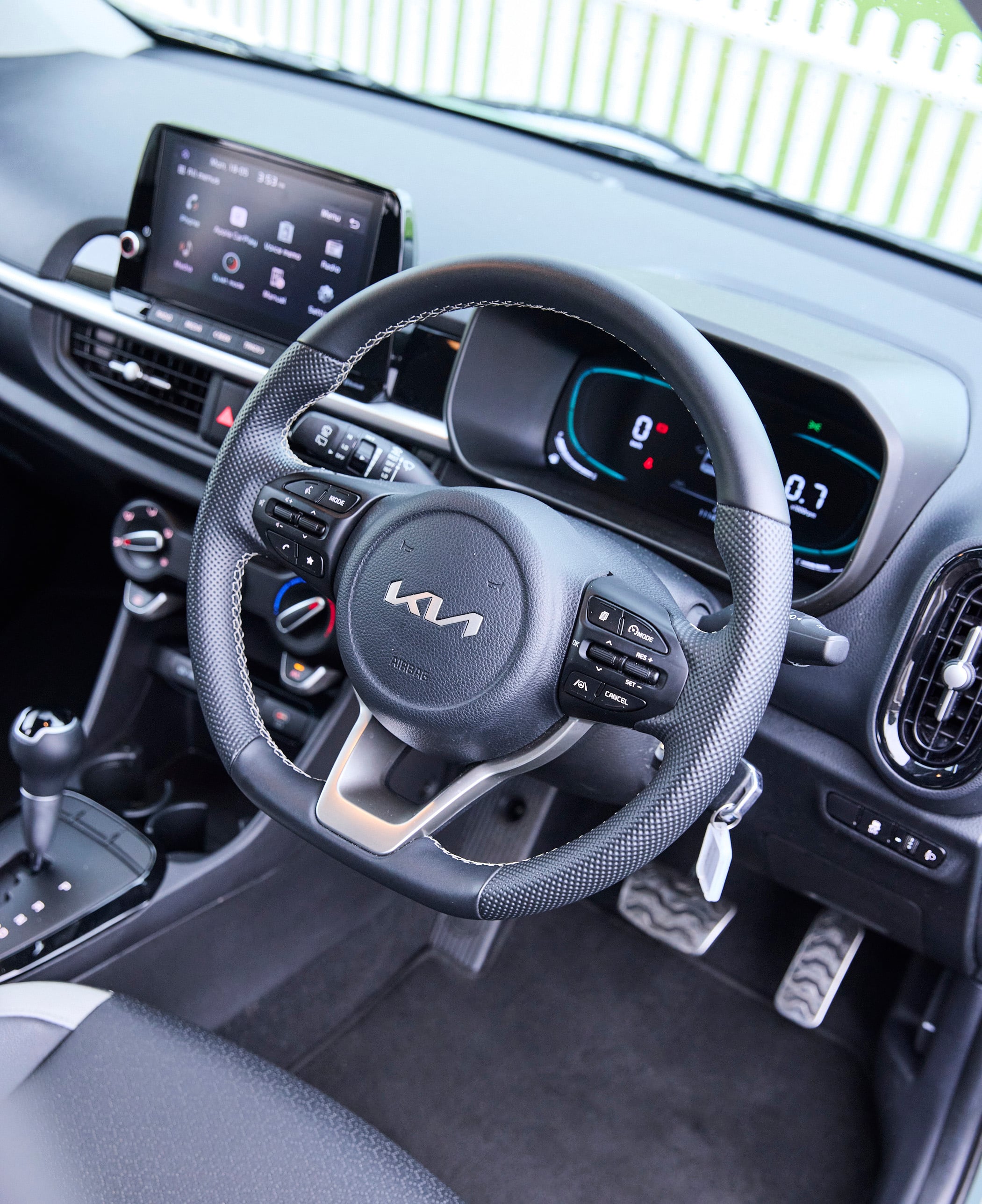 Close-up of a car interior showing the textured steering wheel, digital instrument cluster, and center touchscreen display.