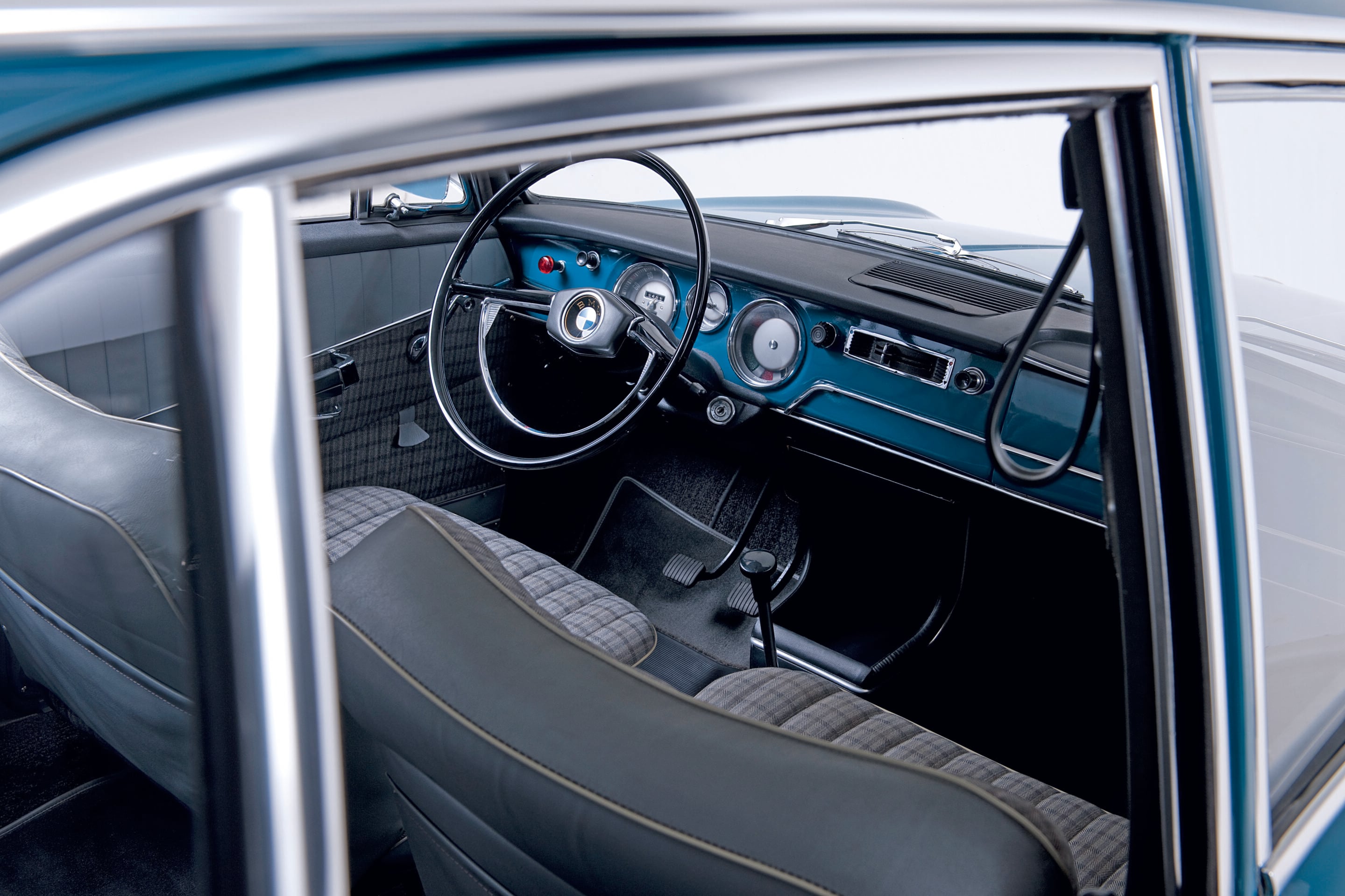 Interior of a vintage blue car showing the steering wheel, chrome accents, and classic dashboard gauges