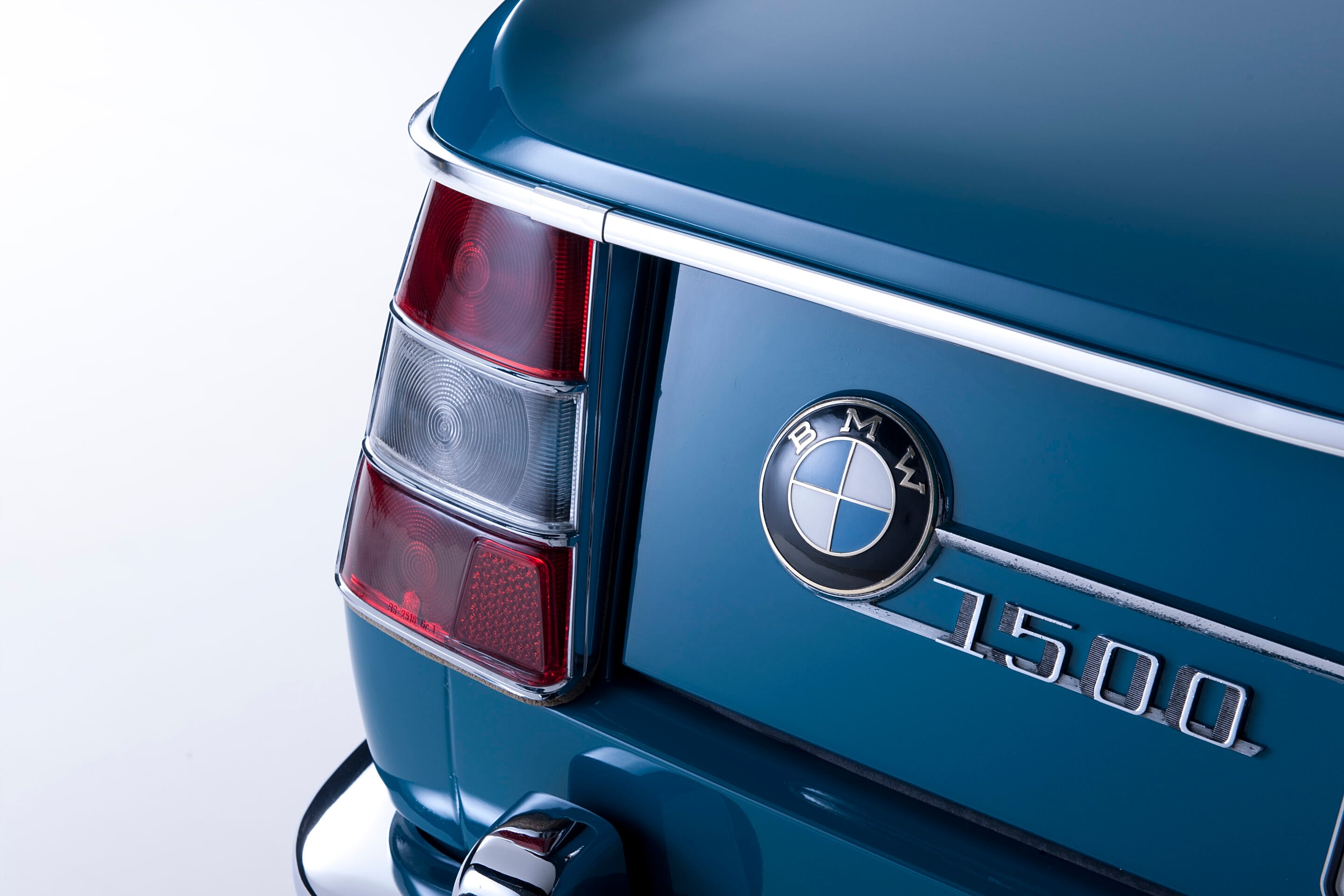 Rear view of a blue BMW showing the taillight, chrome trim, and BMW badge on the trunk.