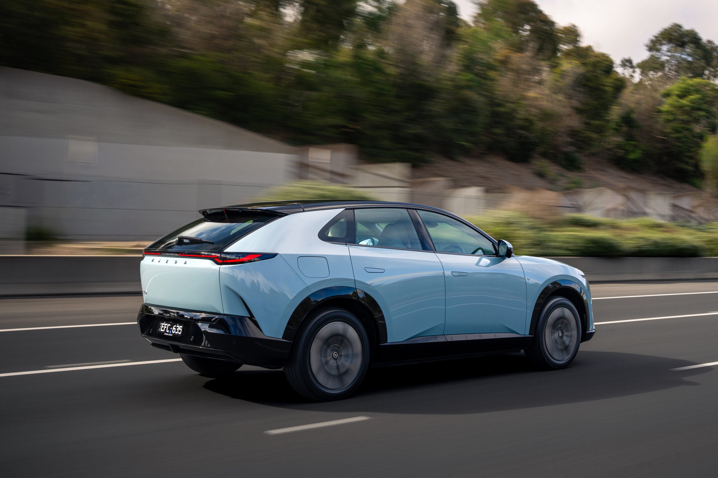 Light blue SUV driving at speed on a multi-lane highway with a blurred background.