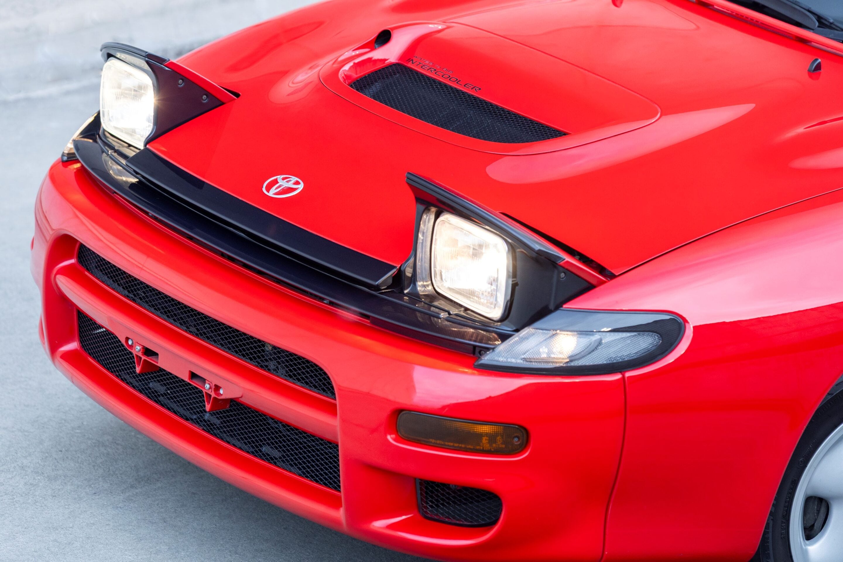 Front view of a red Toyota sports car showing the emblem, grille, and rectangular headlights.