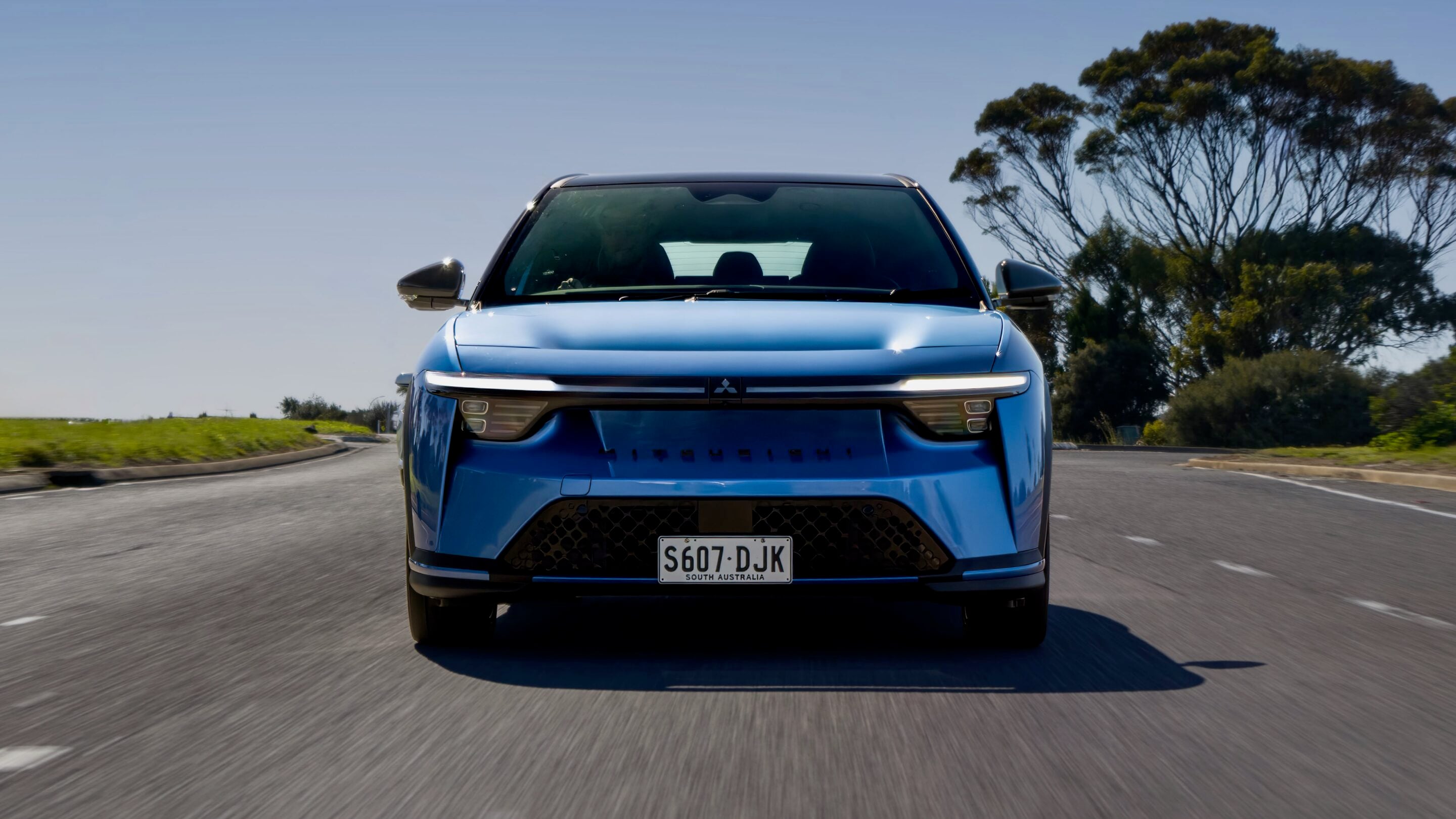 Front view of a blue SUV driving toward the camera on a curved road; license plate S607 DJK (South Australia).