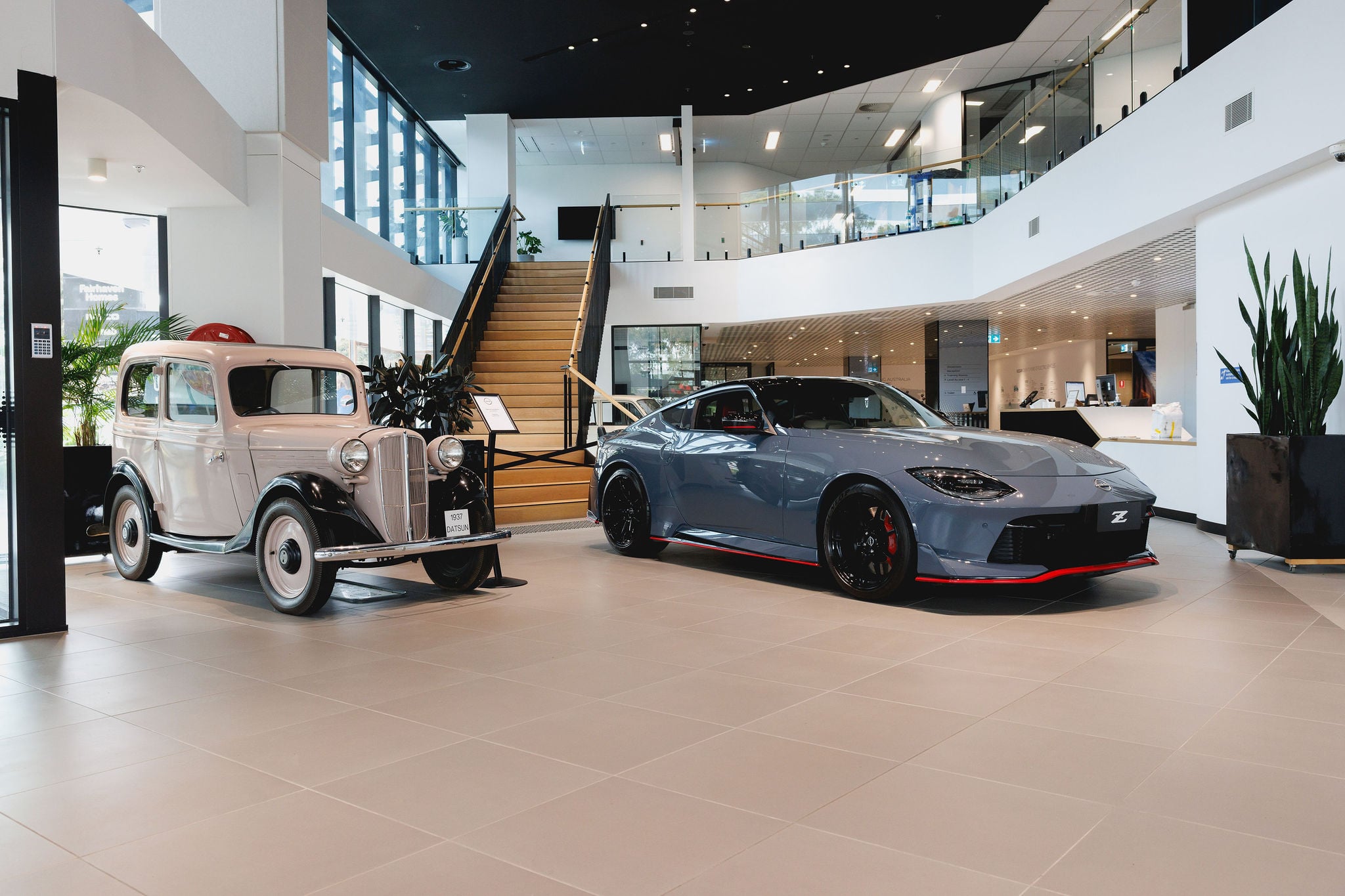 A 1937 Datsun alongside the latest Z NISMO and Nissan Motor Australia's HQ building.