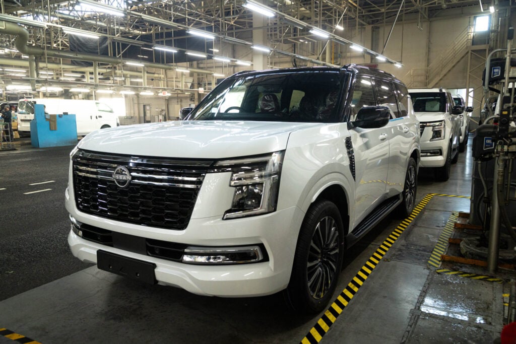White 2027 Nissan Y63 Patrol shown from the front three-quarter angle inside a vehicle manufacturing facility.