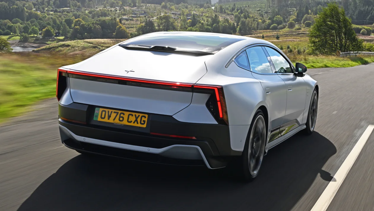 Rear view of a silver electric sedan driving on a rural road, UK plate OV76 CXG.