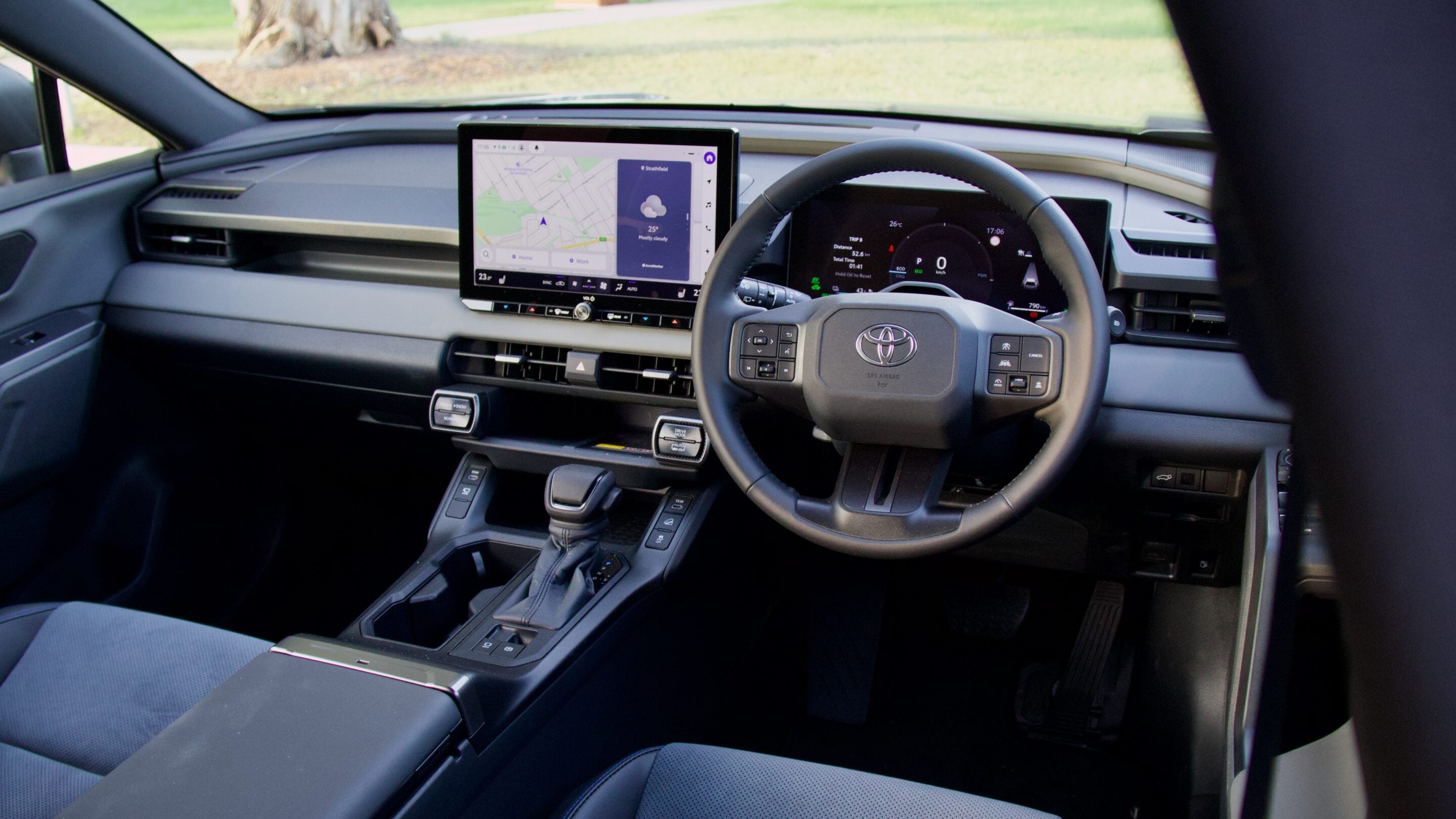 Modern car interior with a left-center touchscreen navigation display and digital instrument cluster behind the steering wheel.