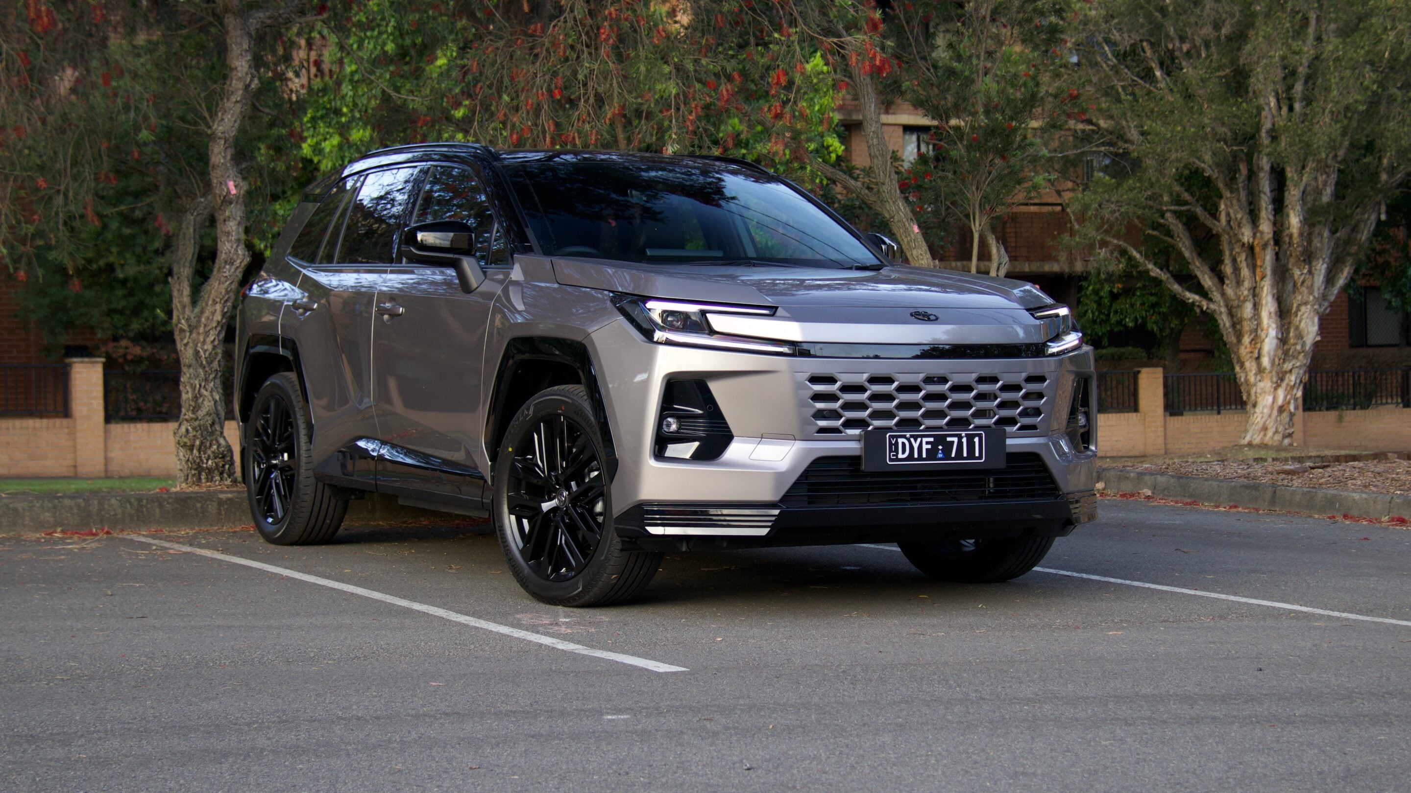Gray SUV parked in a parking lot, front-right angle with a prominent honeycombed grille and dark tinted windows